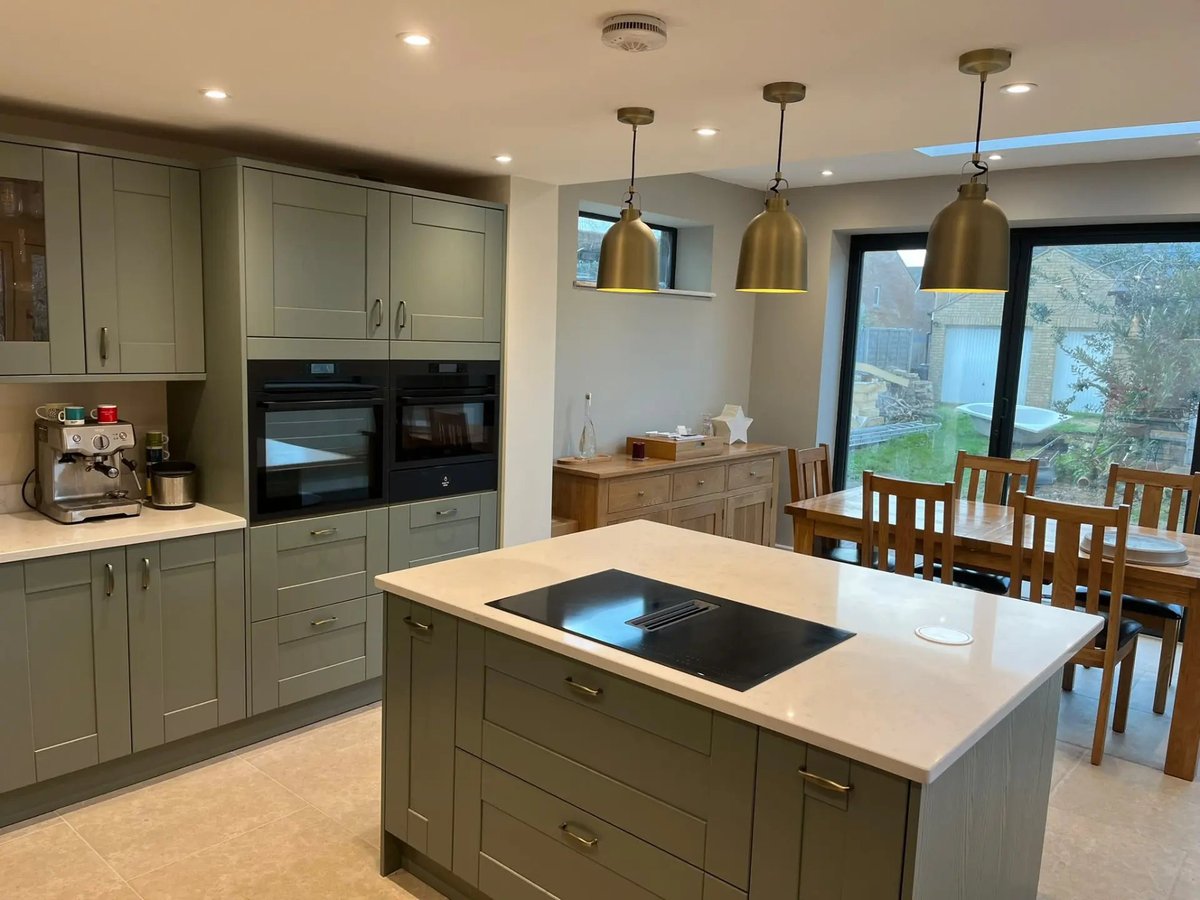 Completed open-plan kitchen with island, quartz worktops and brass pendants, Willingham