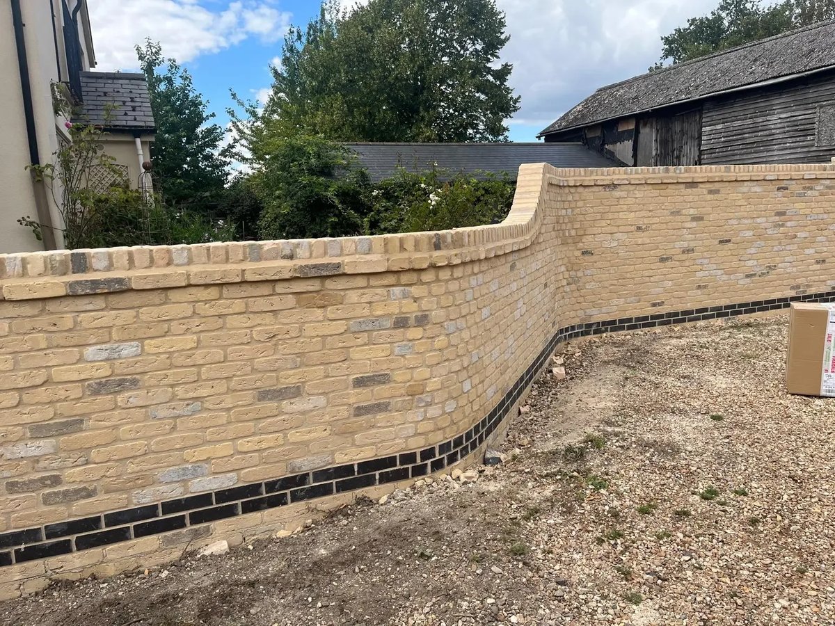 Completed curved buff brick garden wall with shaped top and dark brick detail course