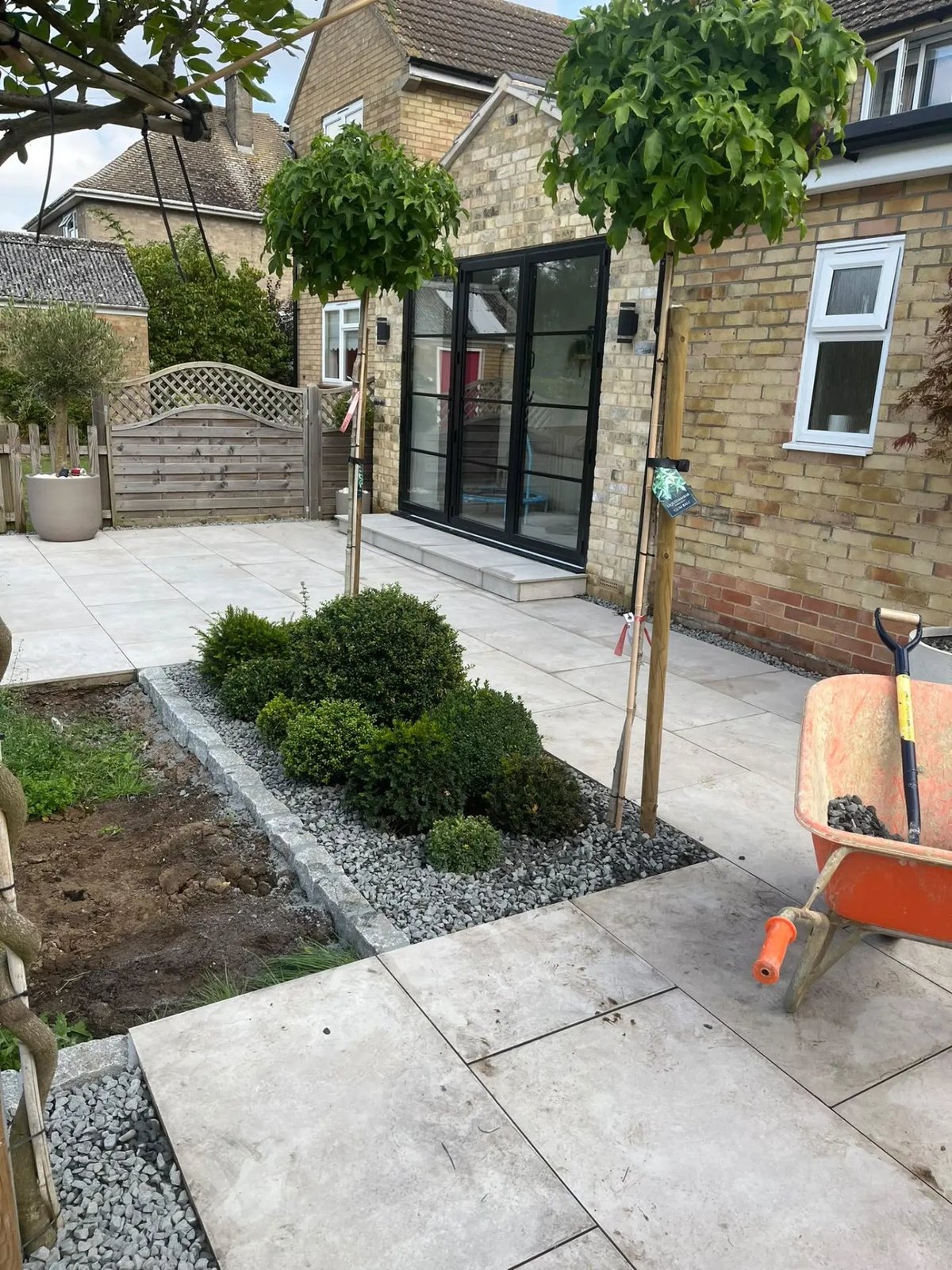 New patio with granite-edged planting beds, slate mulch and young trees, Warboys
