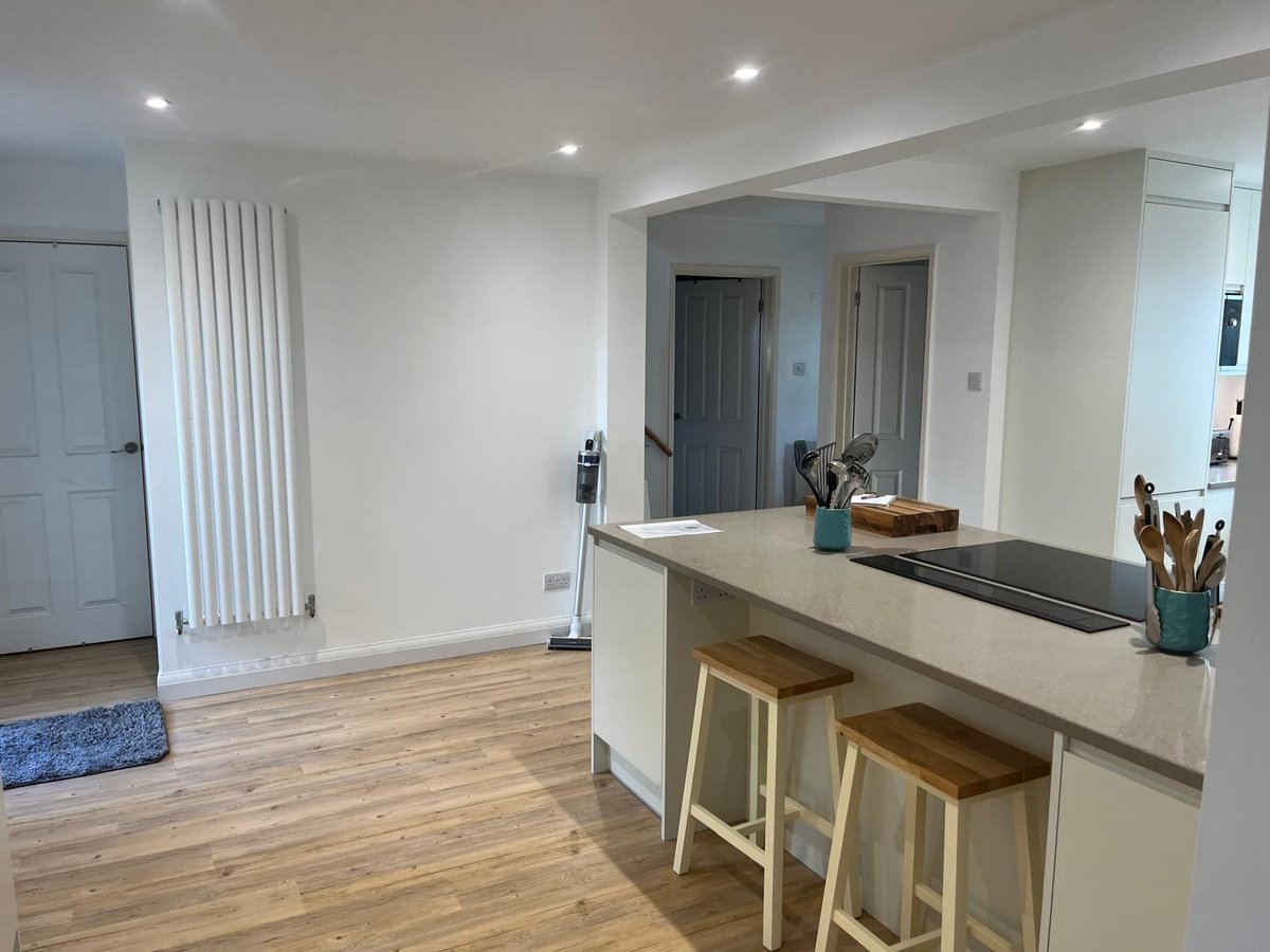 Cream kitchen peninsula with quartz worktop opening into the hallway, Prime Build Services kitchen fitting