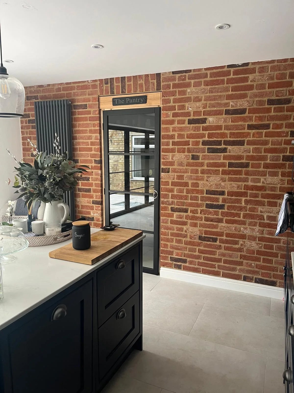 Completed kitchen renovation with exposed brick feature wall and glazed pantry door