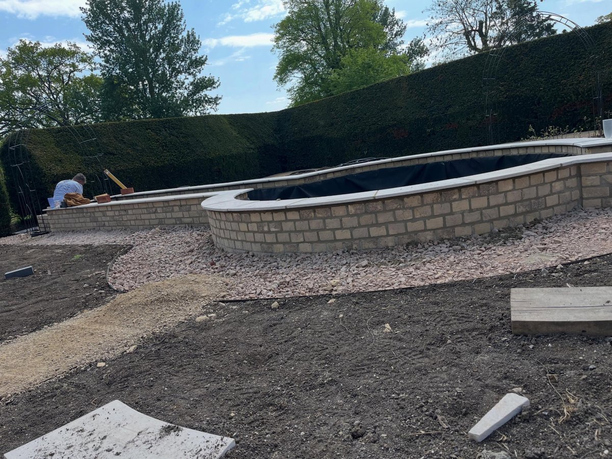 Curved brick water feature being built in a formal garden
