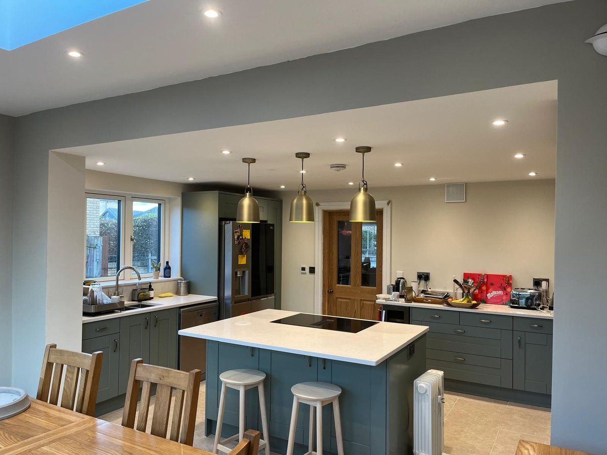 Open-plan kitchen with teal shaker units, quartz island and brass pendants, Prime Build Services kitchen fitting