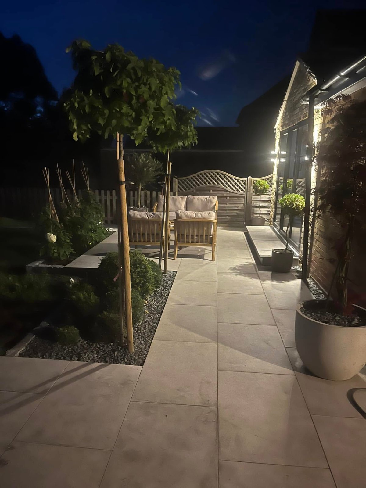 Landscaped garden lit at night showing patio and planted borders