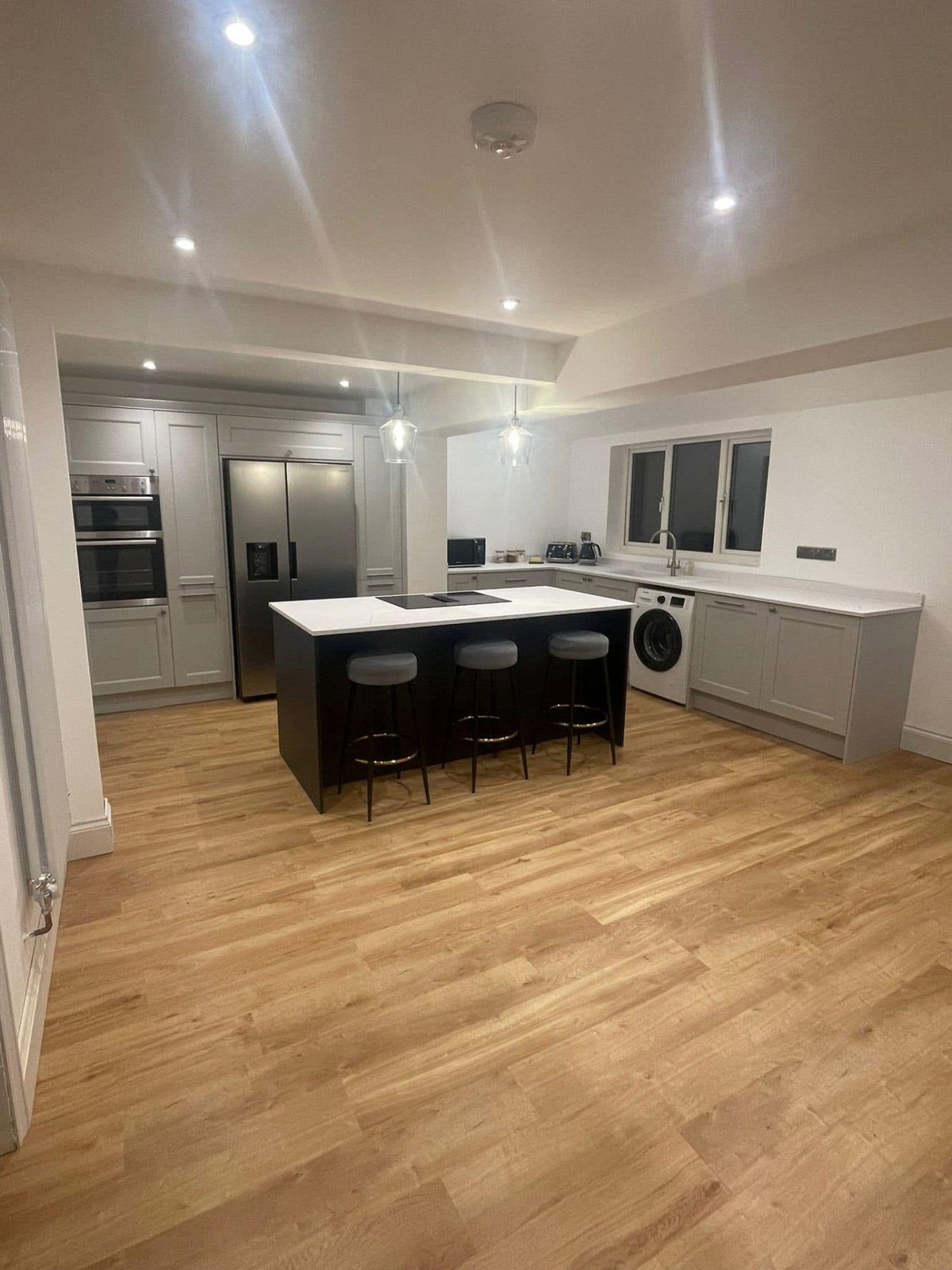 Completed Brampton kitchen renovation showing island seating and wood-effect flooring