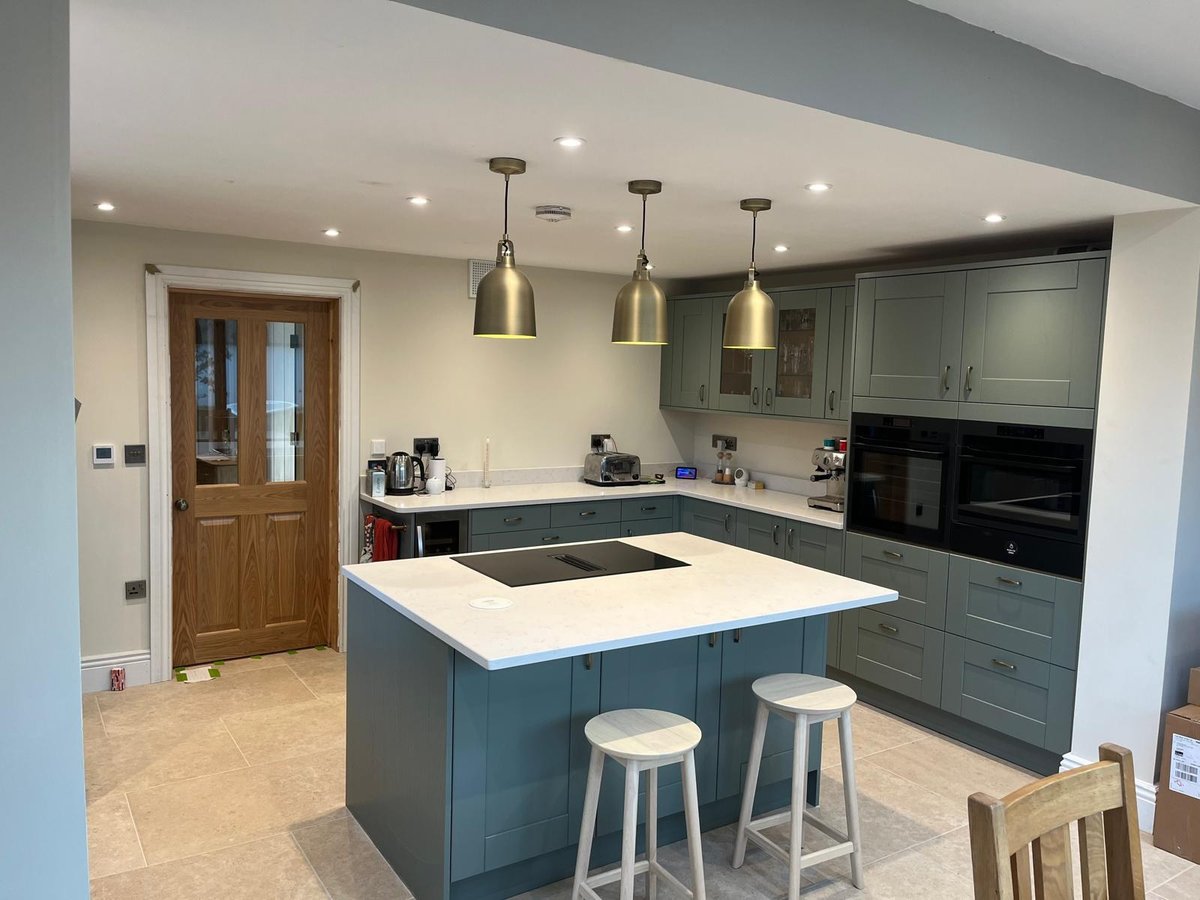 Teal shaker kitchen with quartz island, built-in ovens and travertine floor, Prime Build Services kitchen fitting