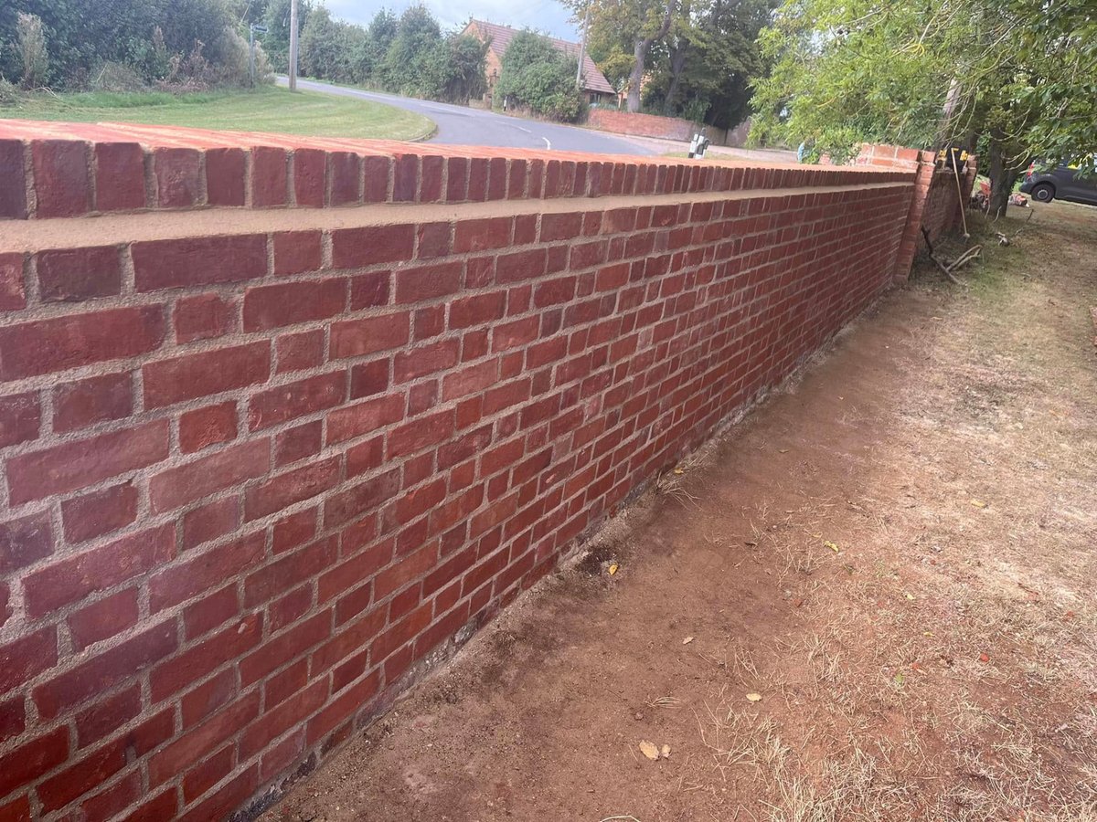 Long red brick wall built along a roadside boundary in Cambridgeshire