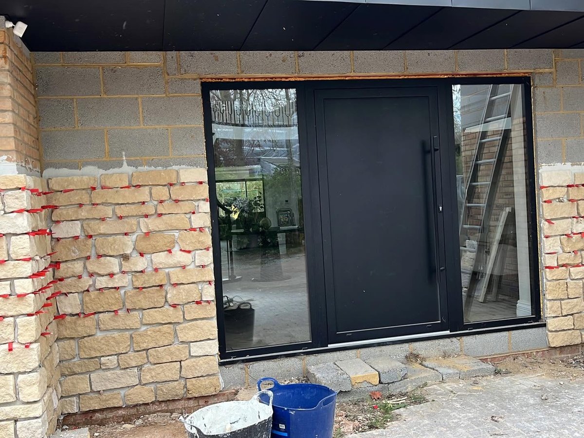 Stone cladding installation in progress around a window reveal