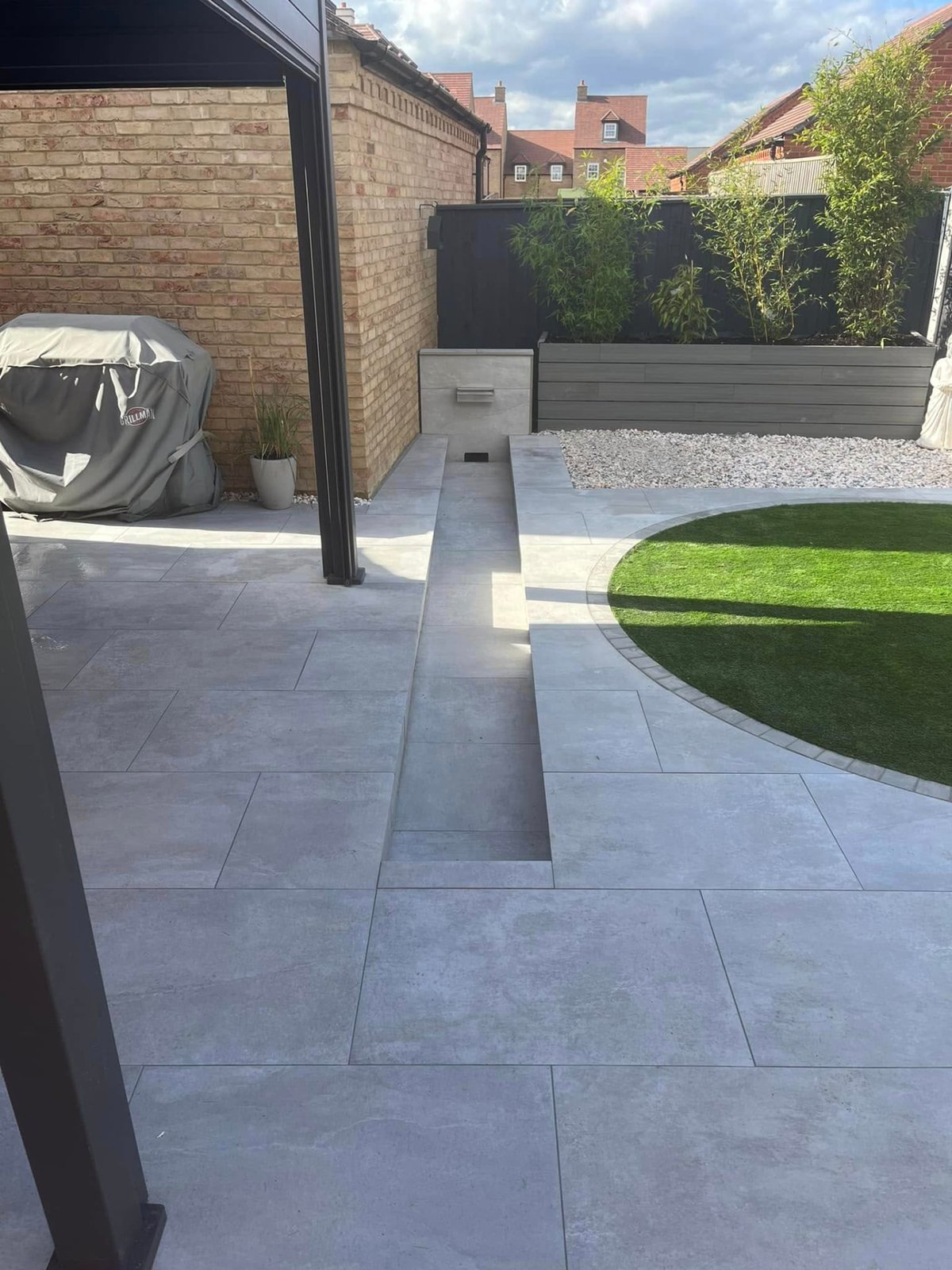 Landscaped garden with shaped artificial lawn, paving and closeboard fencing