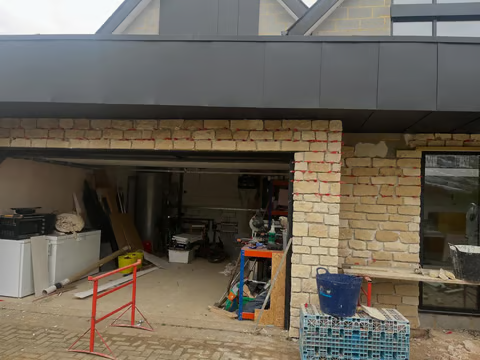 Garage conversion in progress with new structural opening and stone-clad surround, Cambridgeshire