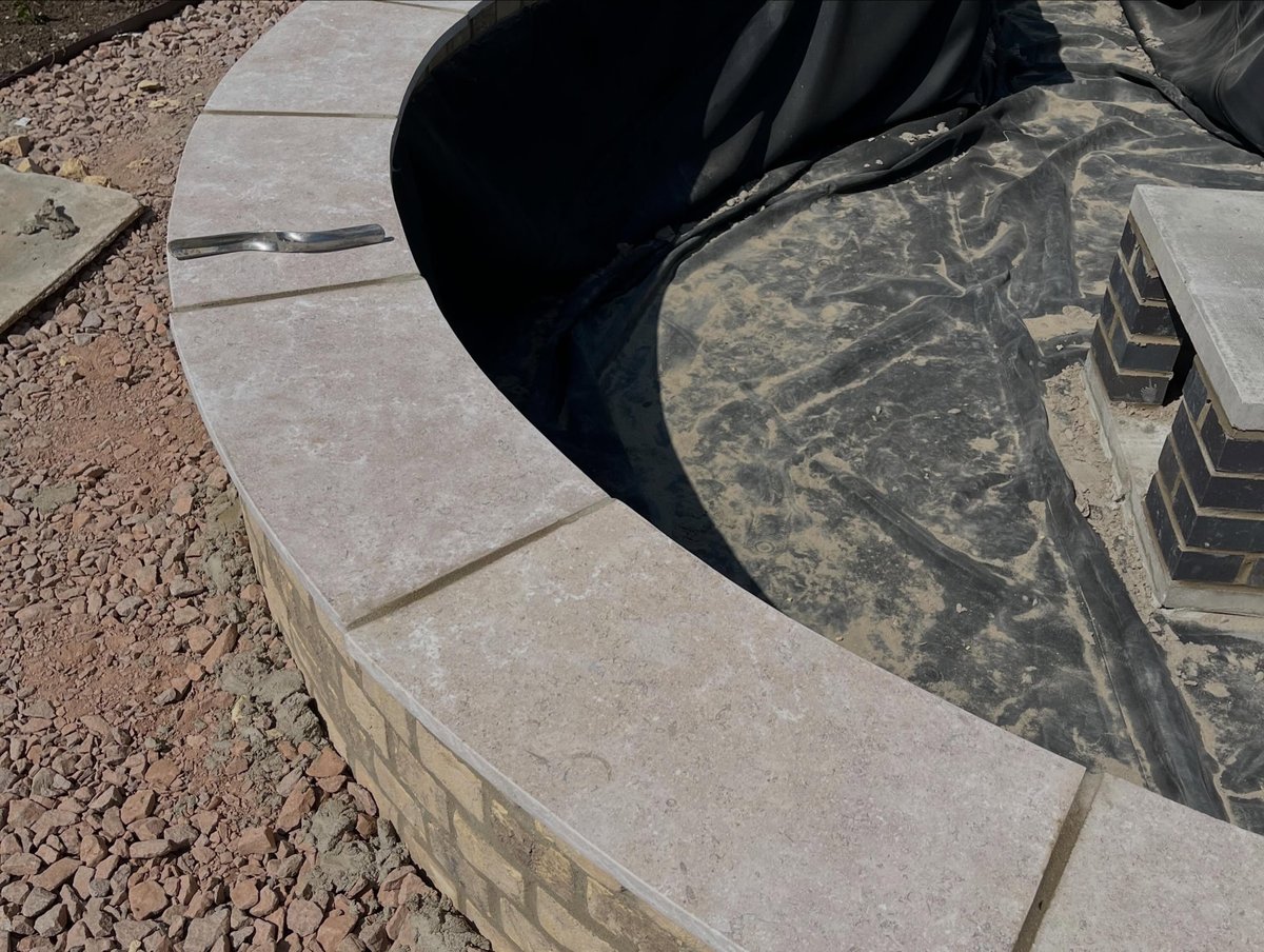 Coping stones and pond liner being fitted to a garden water feature