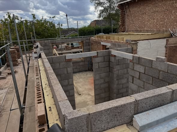 House extension under construction with blockwork walls and structural openings formed