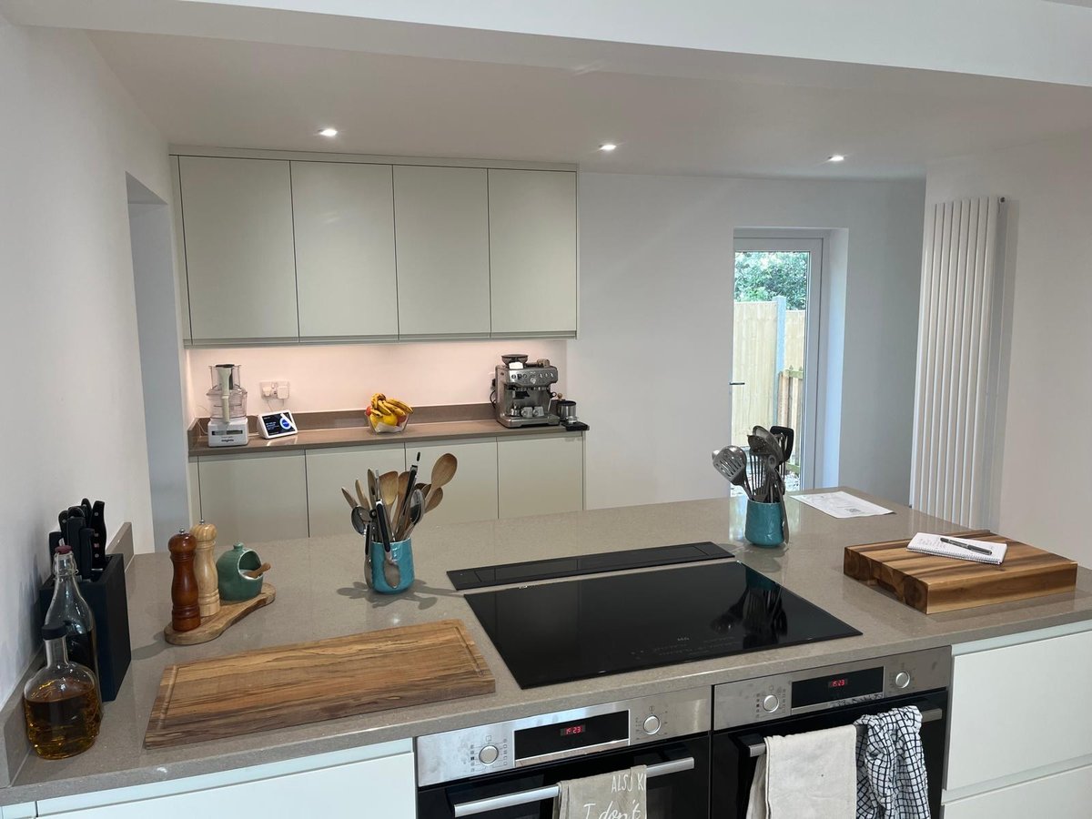 Pale handleless kitchen with quartz peninsula and induction hob, Prime Build Services kitchen fitting