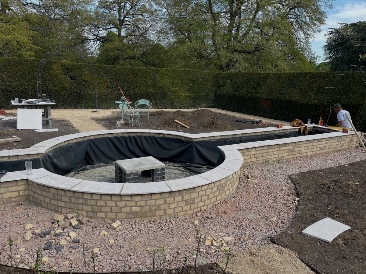 Lined curved water feature under construction in a formal garden