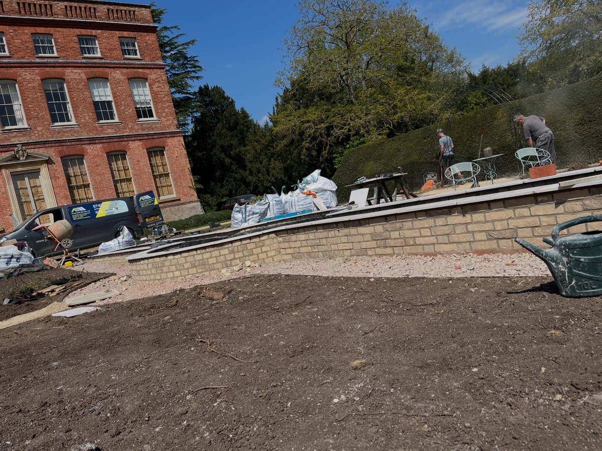 Part-built brick water feature in front of a red brick building