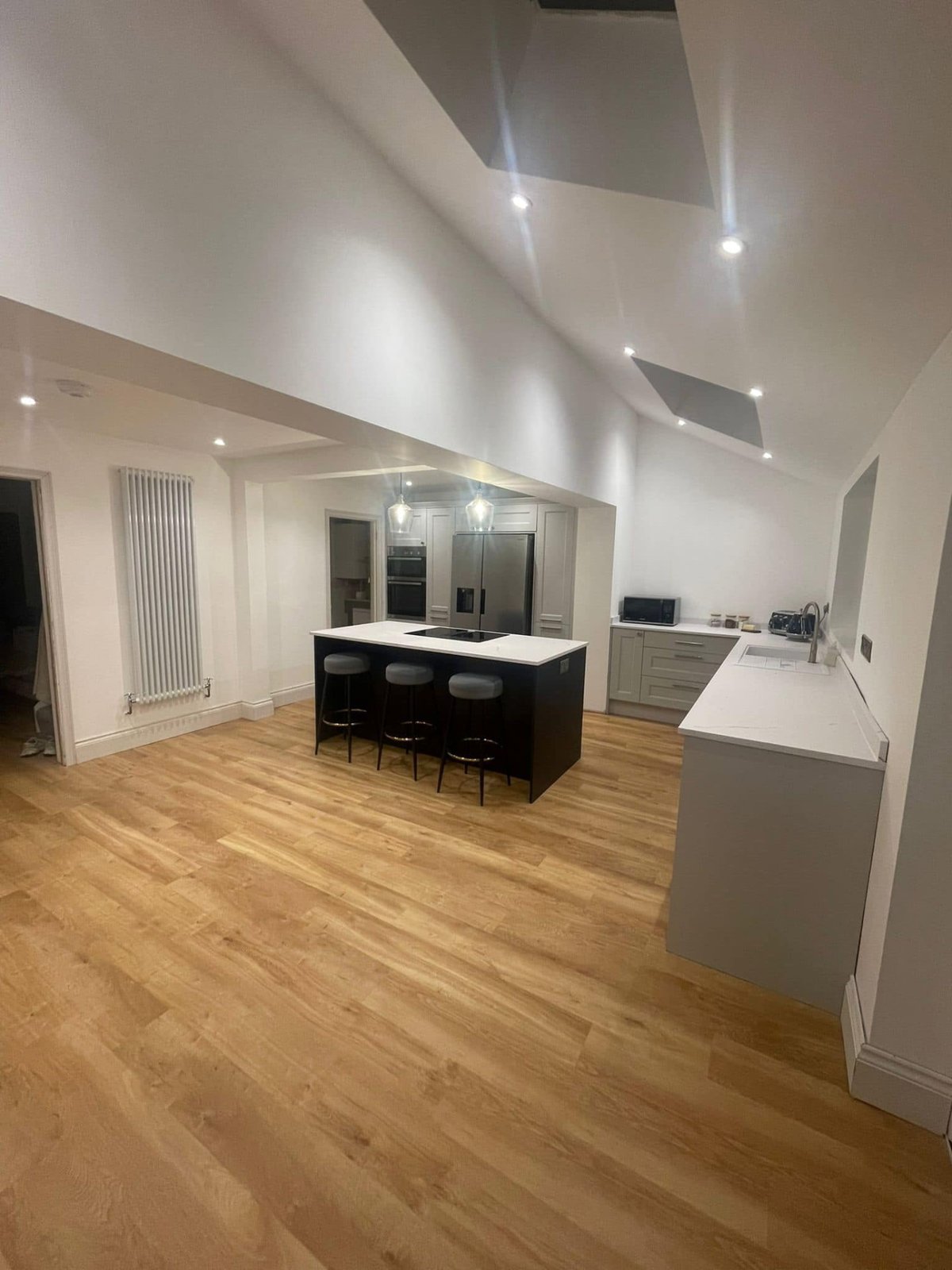 Bright kitchen renovation in Brampton with pale cabinetry, dark island and white worktops