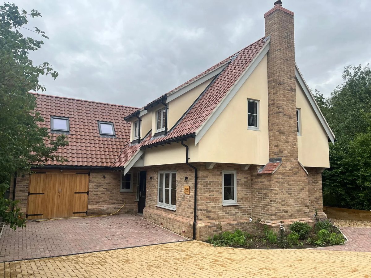 Finished new-build home with tiled roof, brick lower walls and timber garage doors