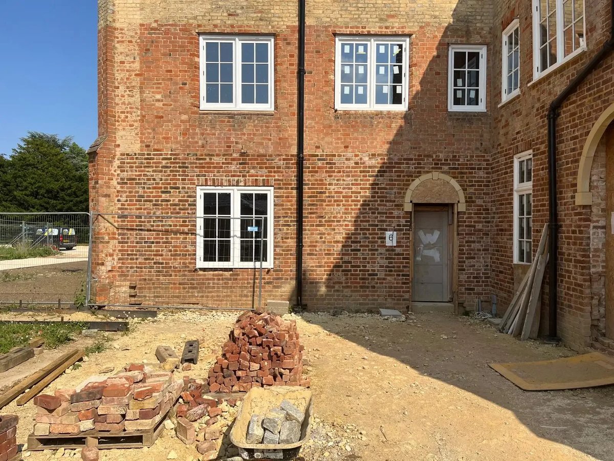 Historic brick building undergoing exterior restoration around arched doorways