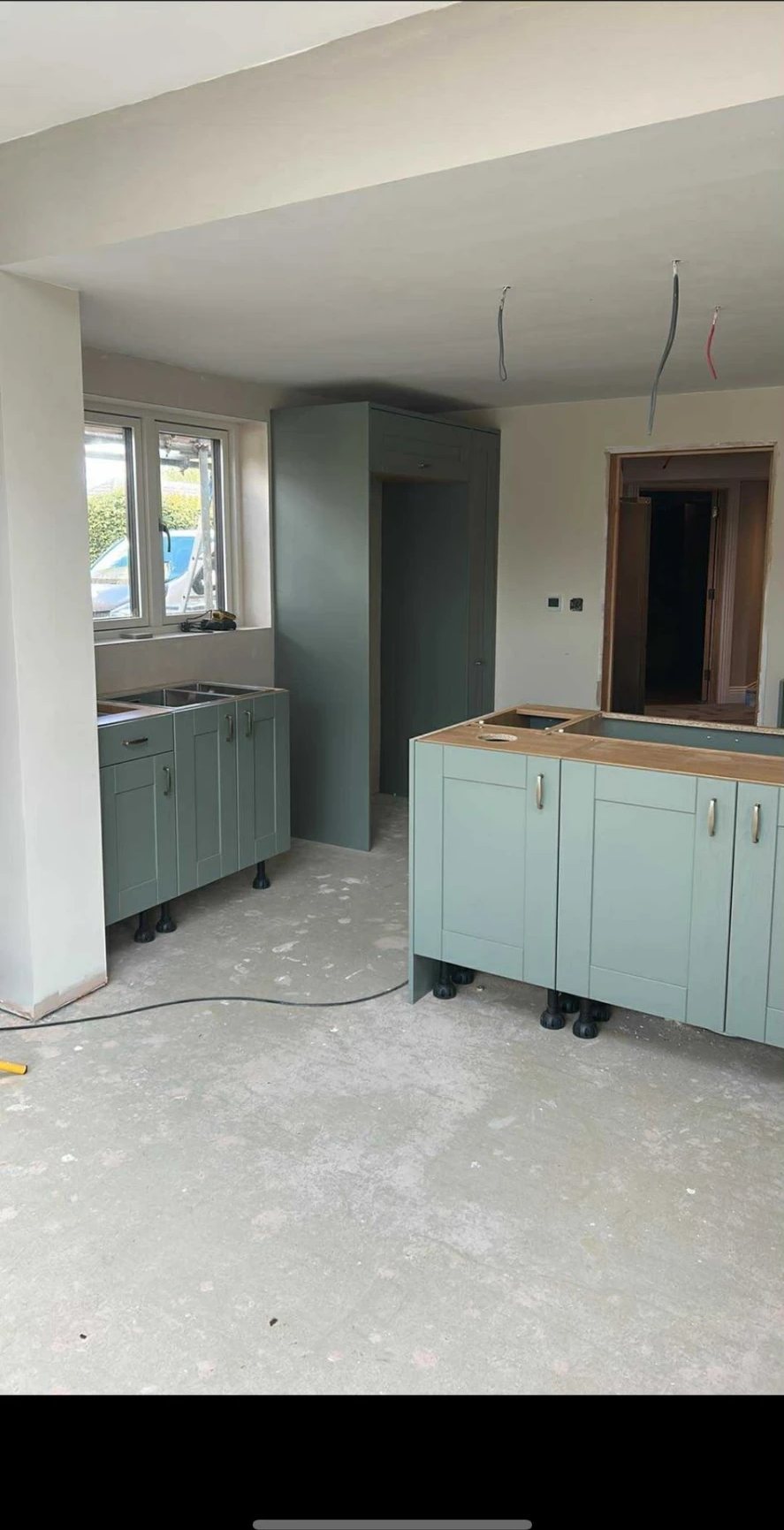 Green shaker kitchen units being fitted in the new open-plan space, Willingham