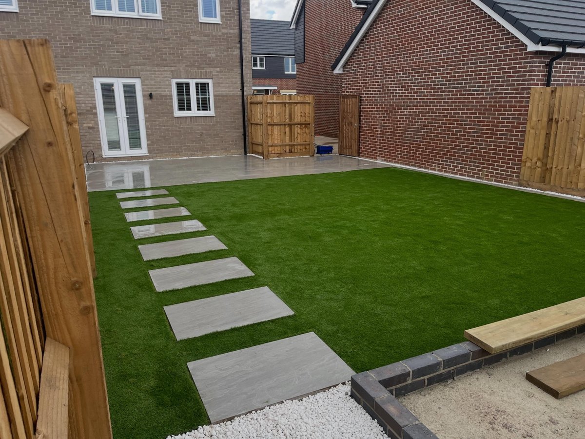 New timber fence panels enclosing a back garden with artificial grass and stepping-stone path